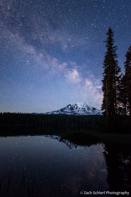 A dark blue twilight sky is bisected by the glow of the Milky Way, and reflected in a tranquil pond.